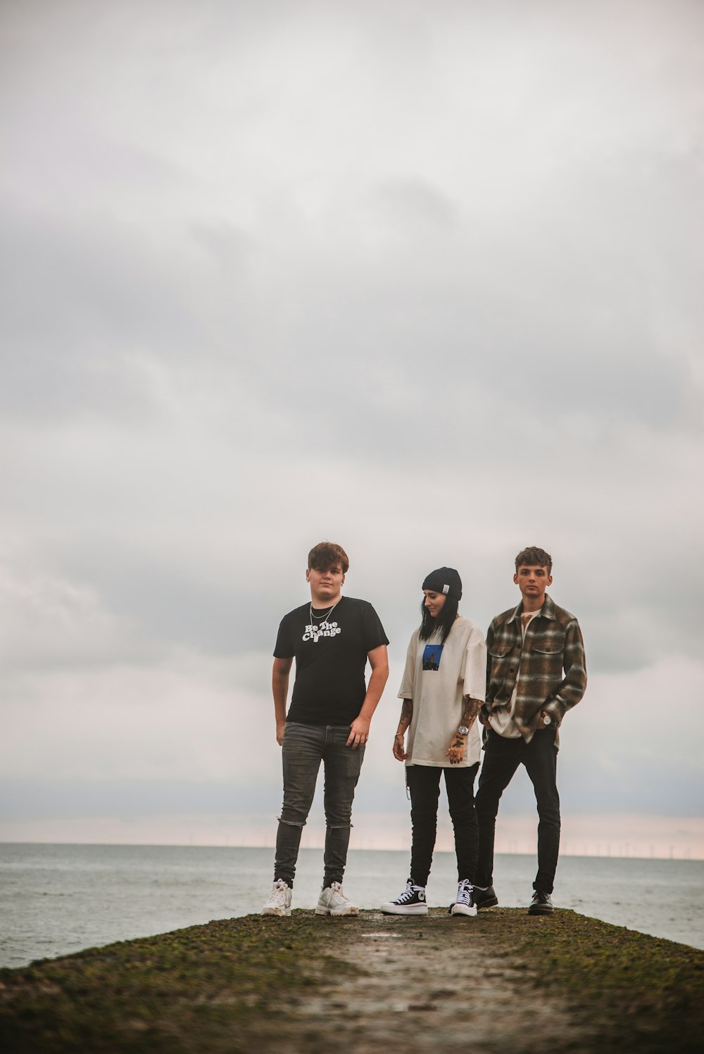 three people standing on a rock near the ocean