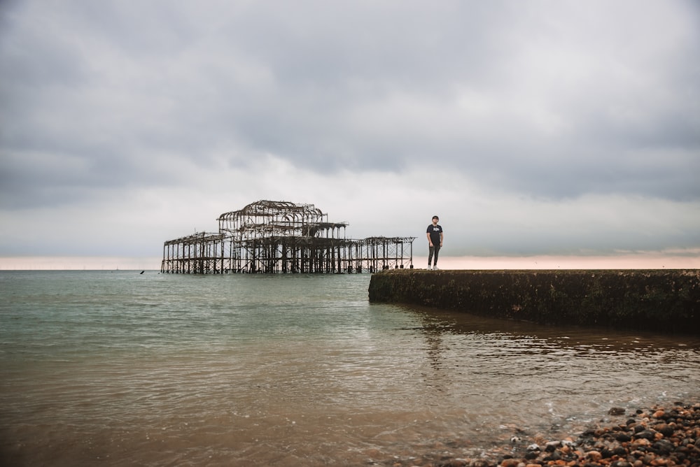 a man standing on the edge of a pier next to the ocean