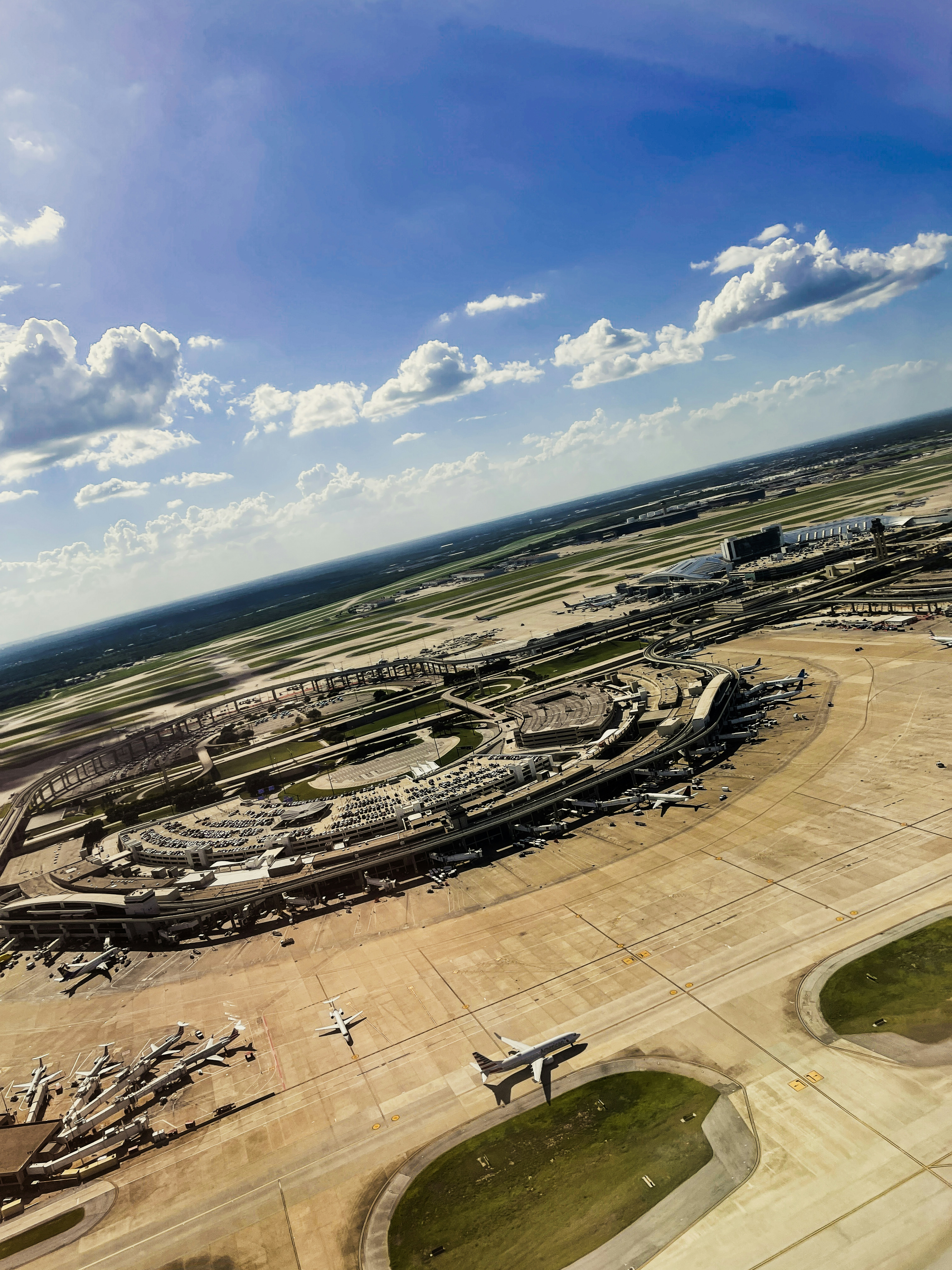 Aerial view of busy airport terminal with planes on tarmac, bright daytime, clear blue sky