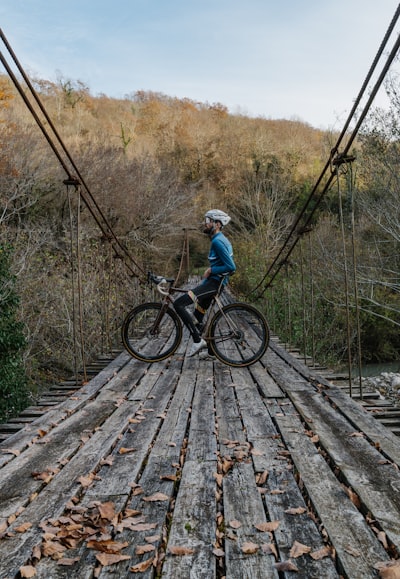 Guy on a bike ok a wooden bridge with a forest backdrop