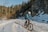 a man riding a bike down a snow covered road