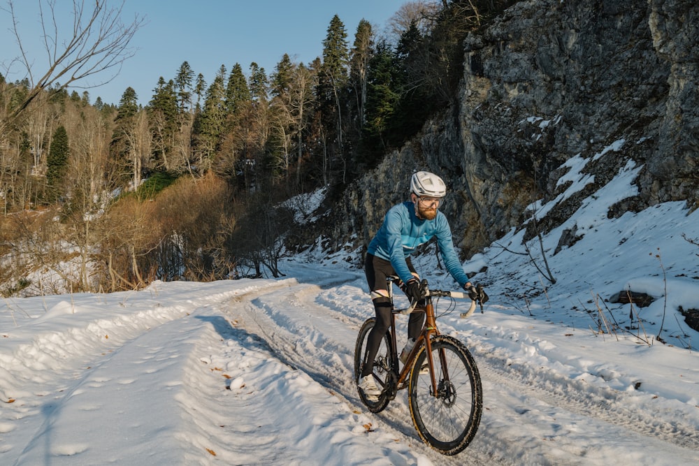 a man riding a bike down a snow covered road