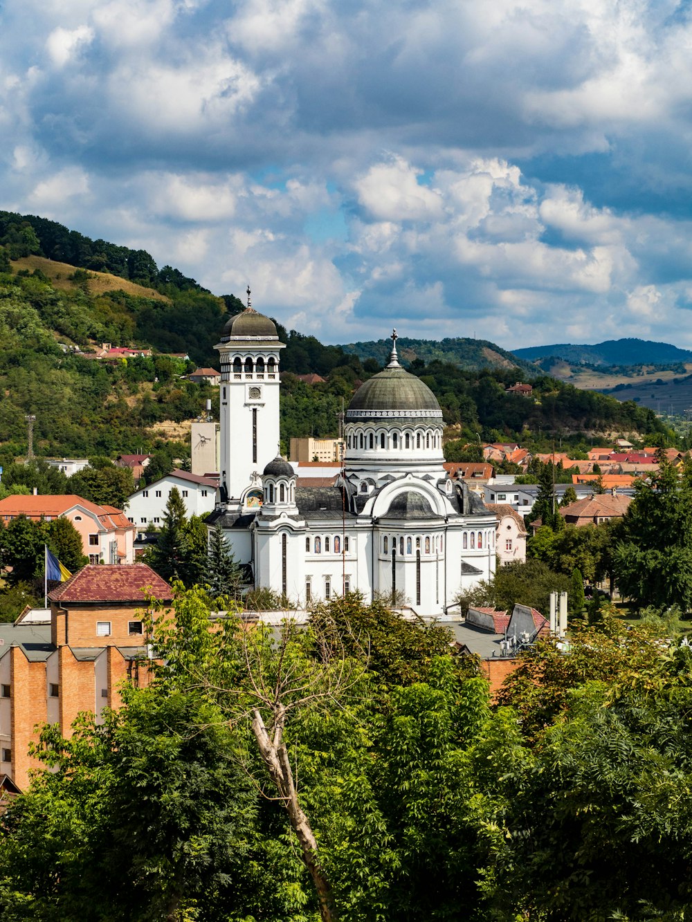 a large white building surrounded by trees and hills