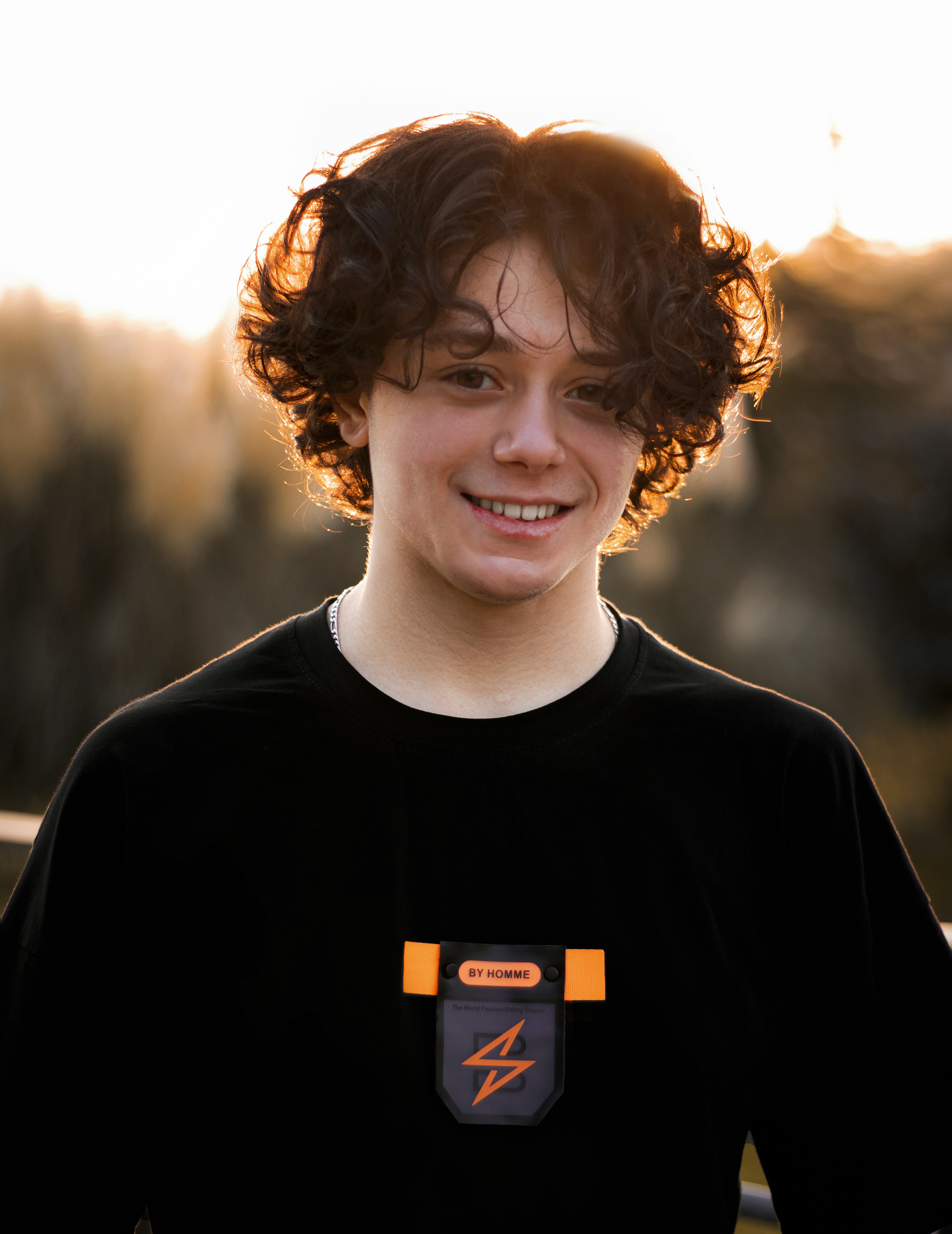 a young man with curly hair wearing a black shirt