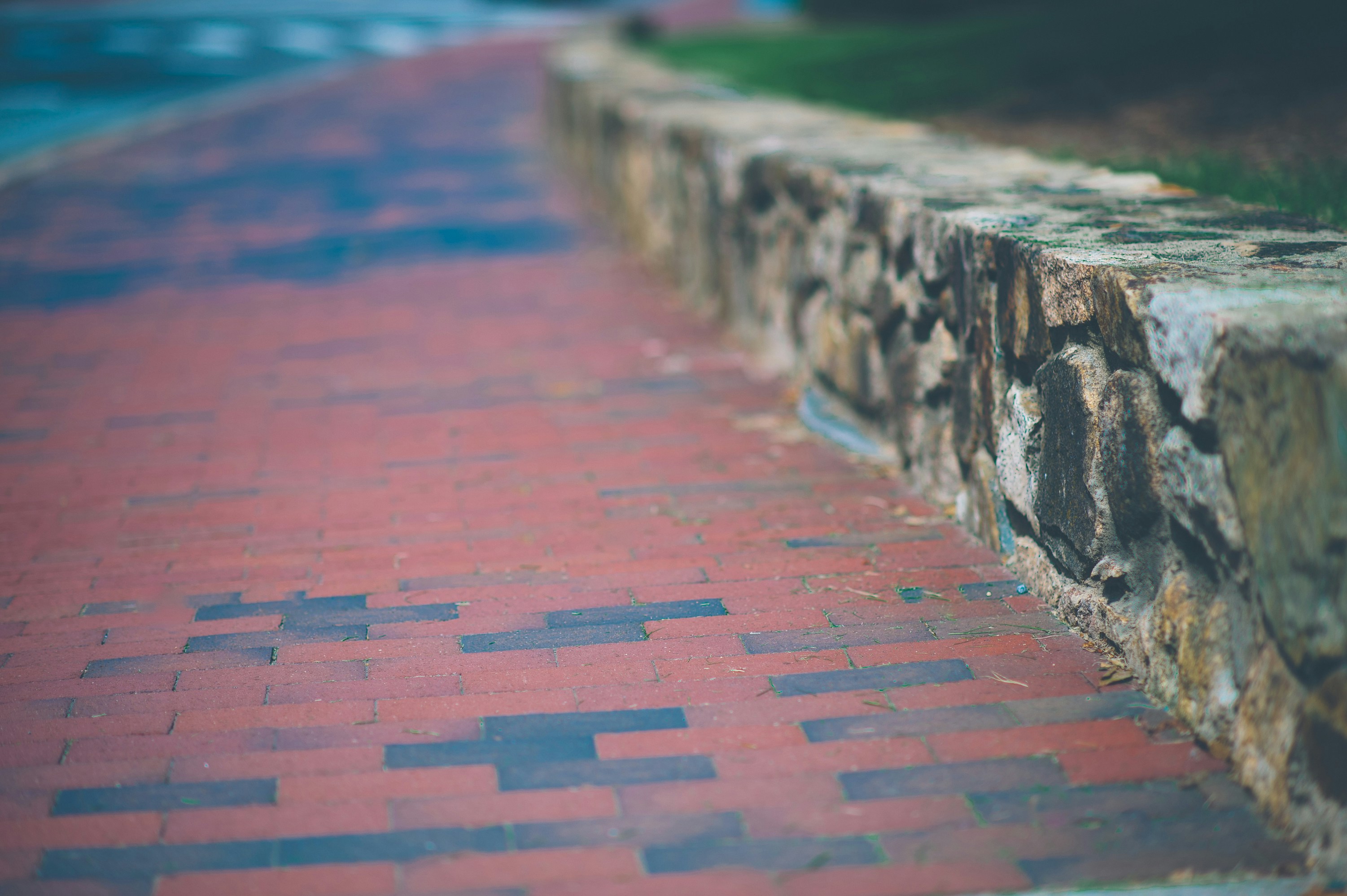 a brick sidewalk with a stone wall and grass