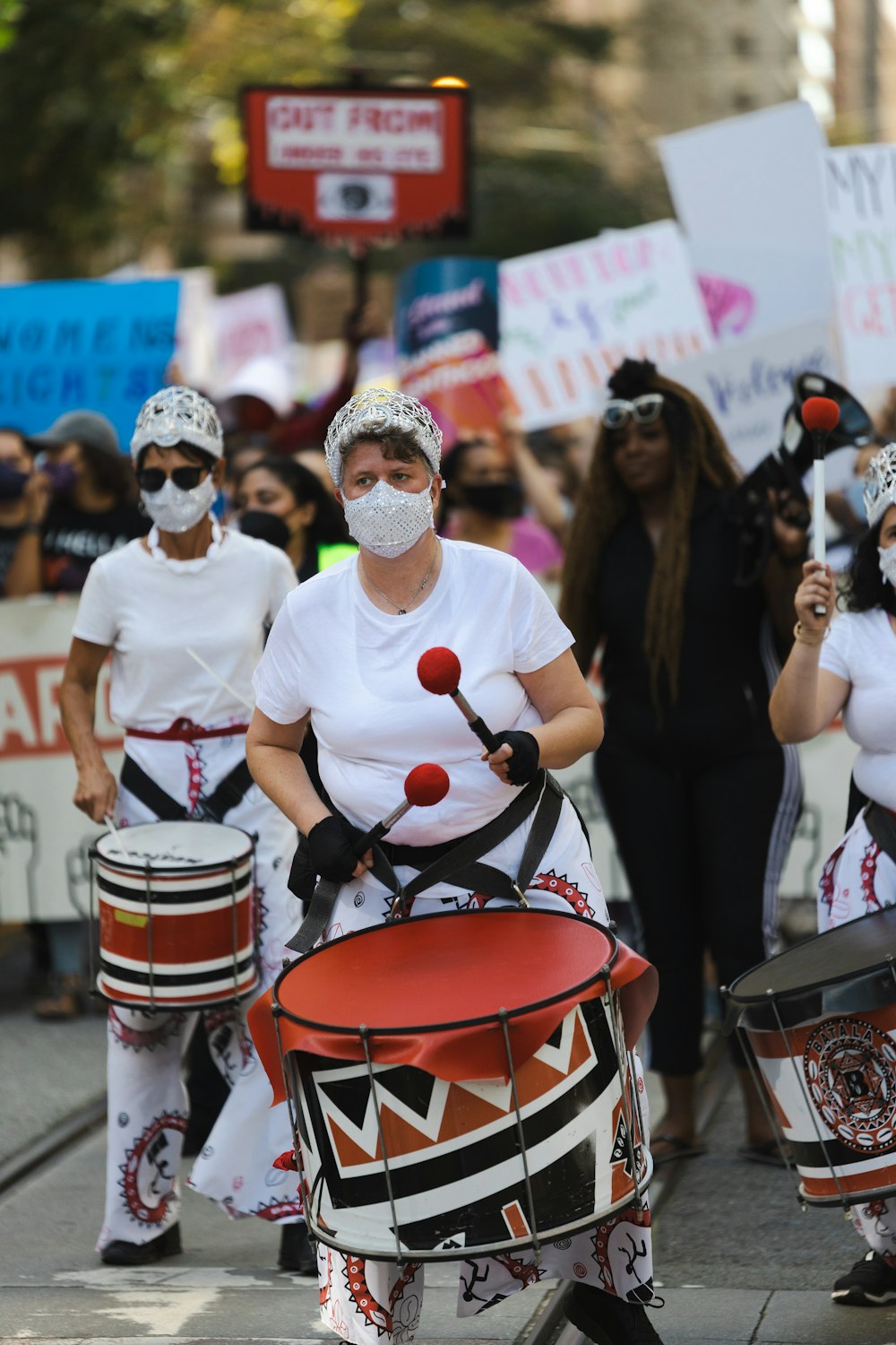 a group of people with masks and drums