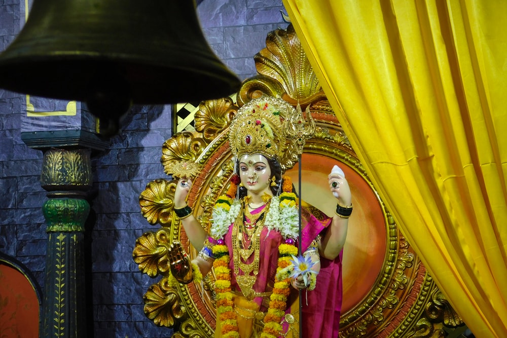 a statue of a hindu god in front of a bell