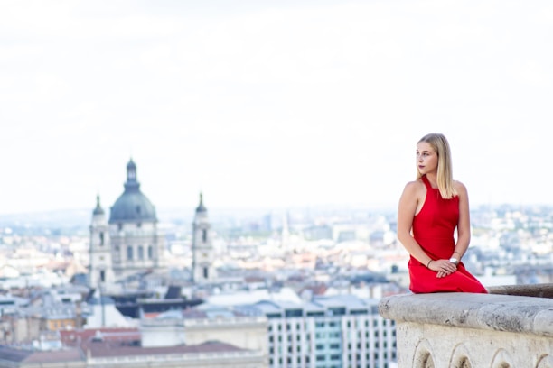 a woman in a red dress sitting on a ledge