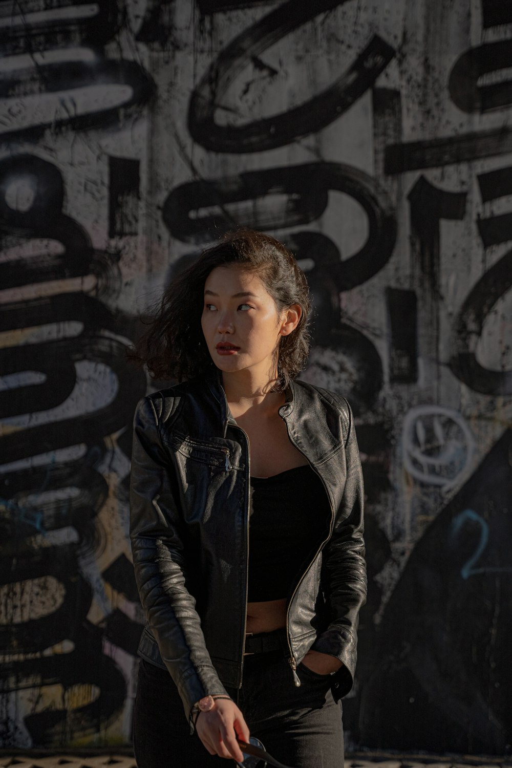 a woman standing in front of a graffiti covered wall