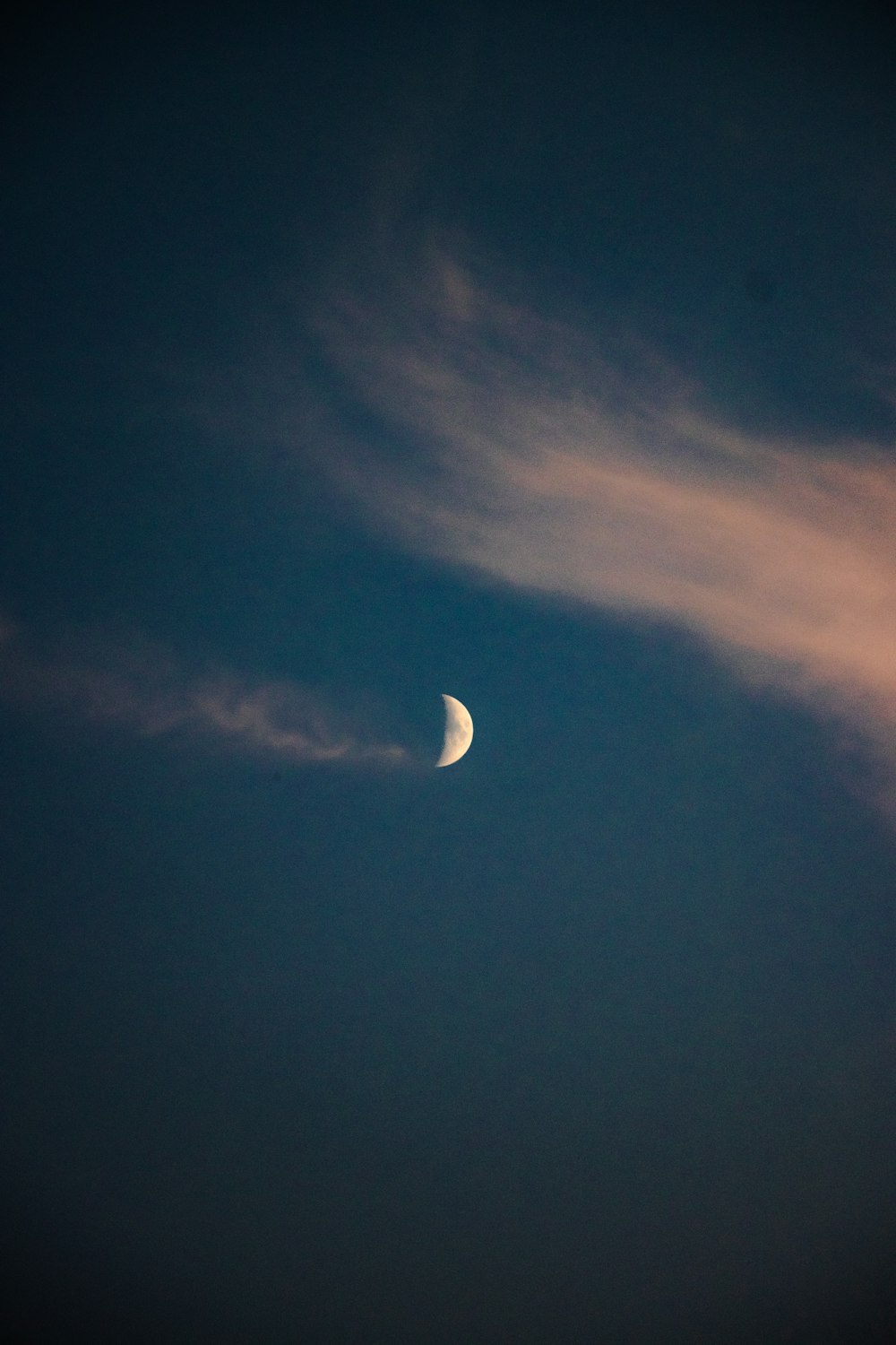 a half moon in the sky with clouds