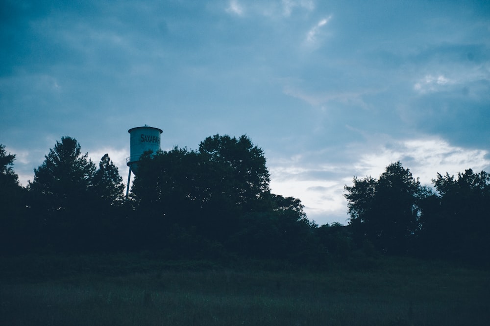 a water tower is silhouetted against a cloudy sky