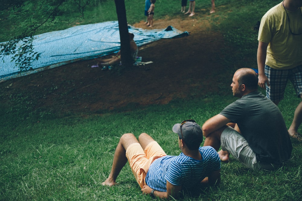 a group of people sitting on top of a lush green field