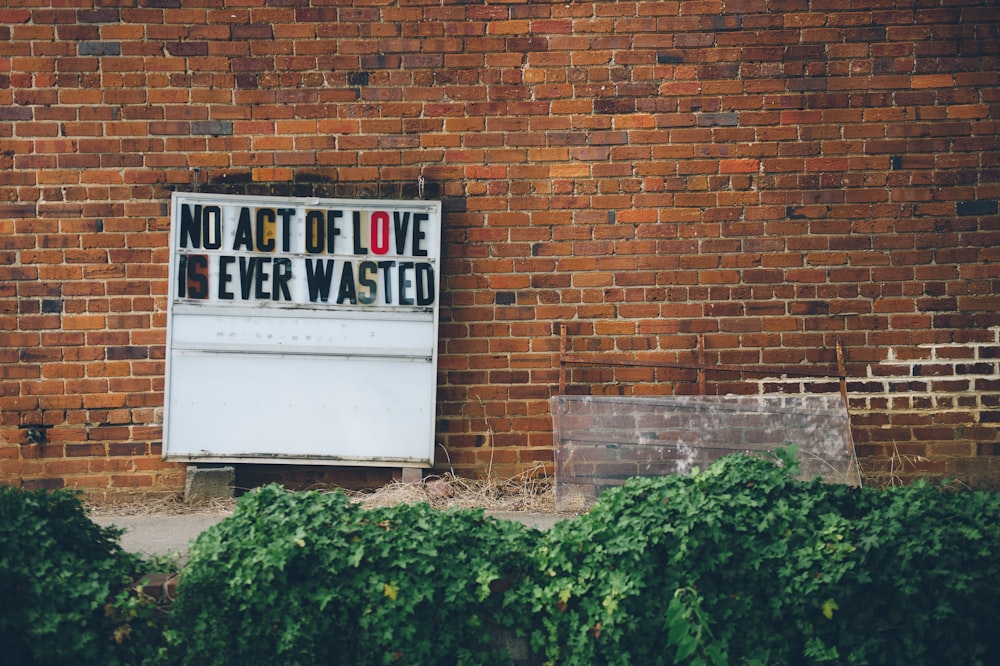 a sign on a brick wall that says no act of love ever wasted