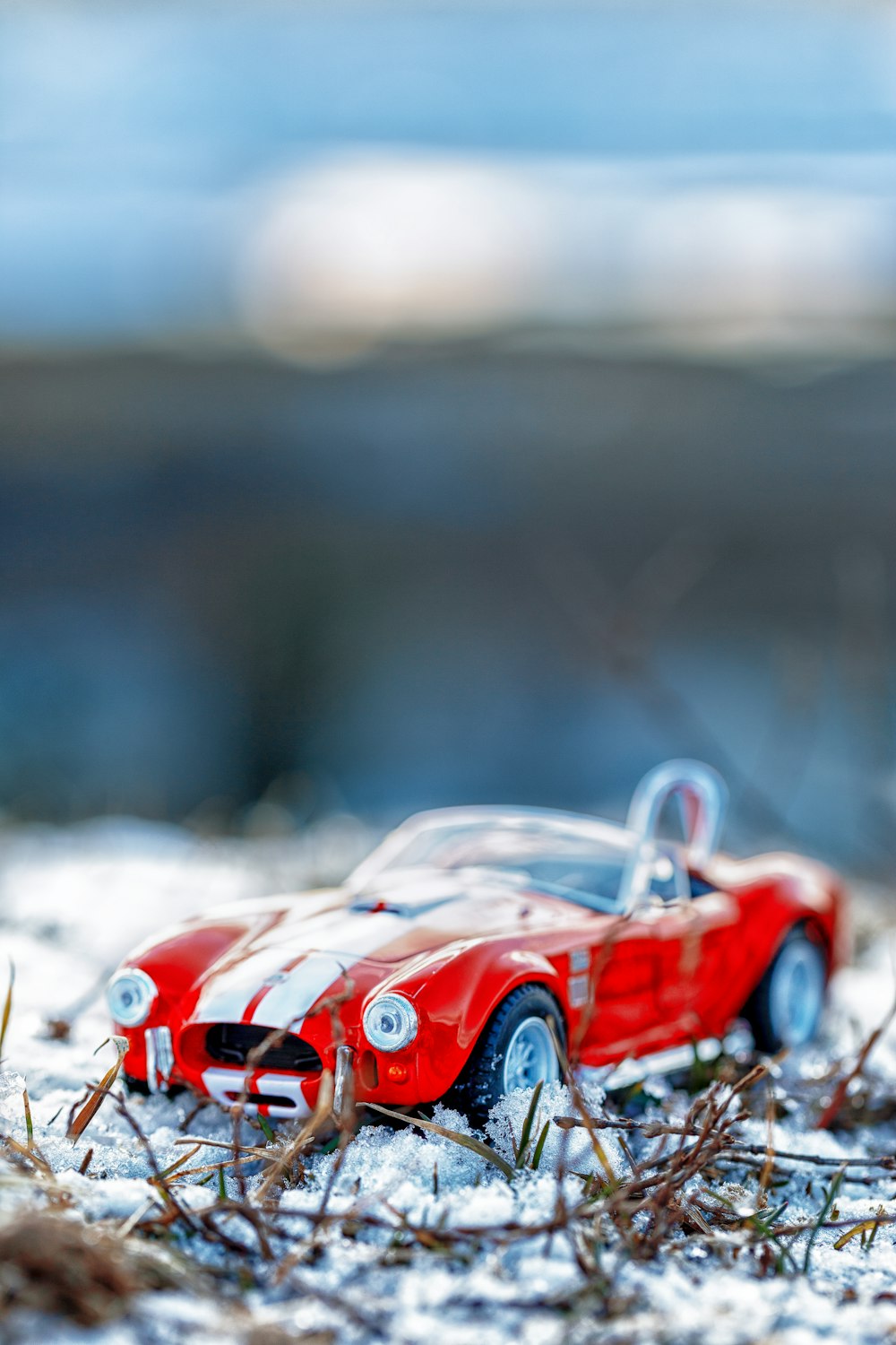 a red toy car sitting on top of snow covered ground
