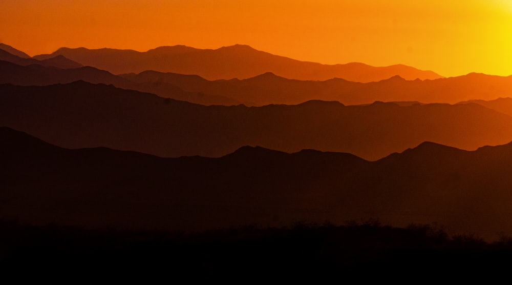 the sun is setting over a mountain range