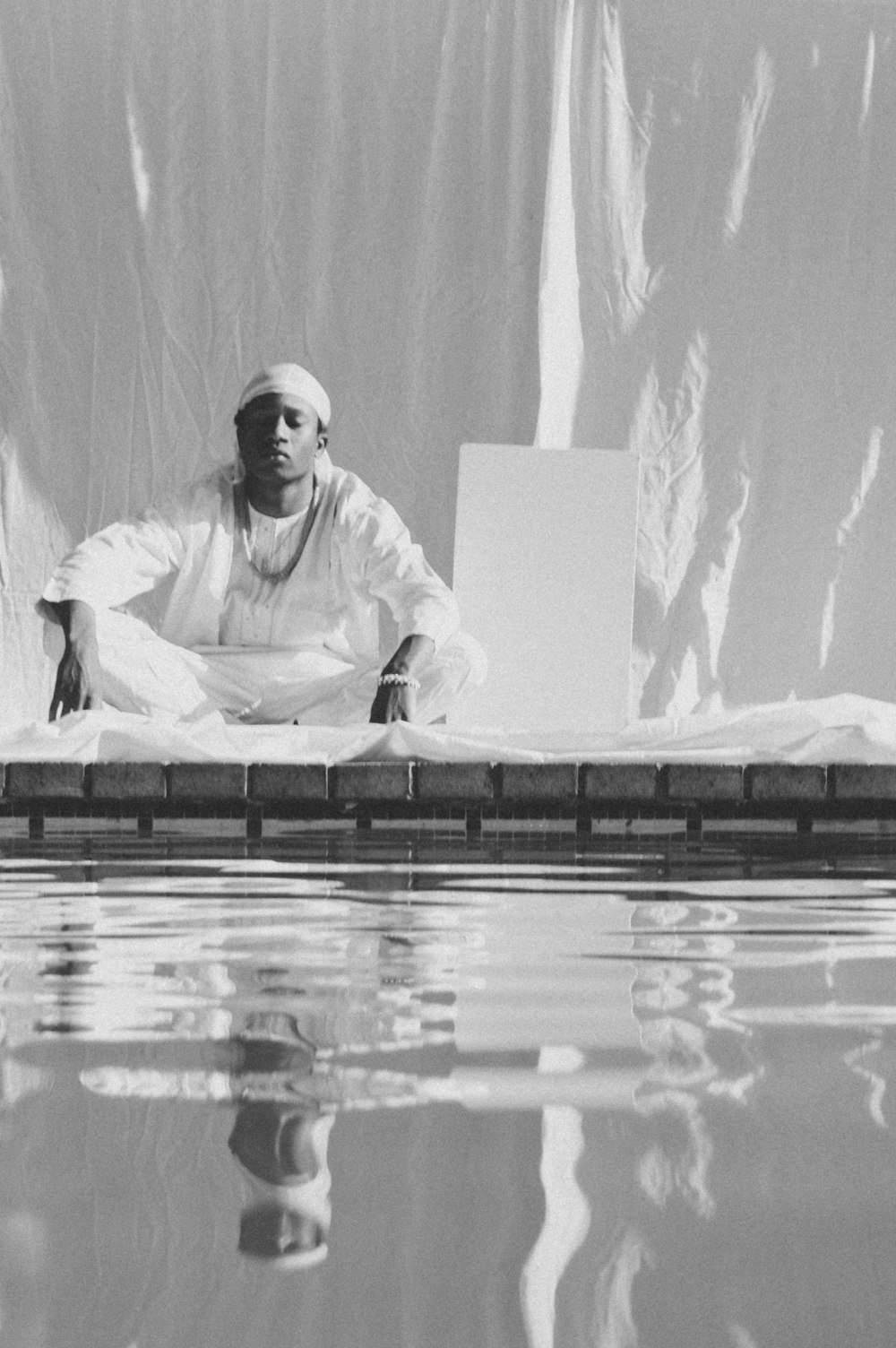 a man sitting on the edge of a swimming pool