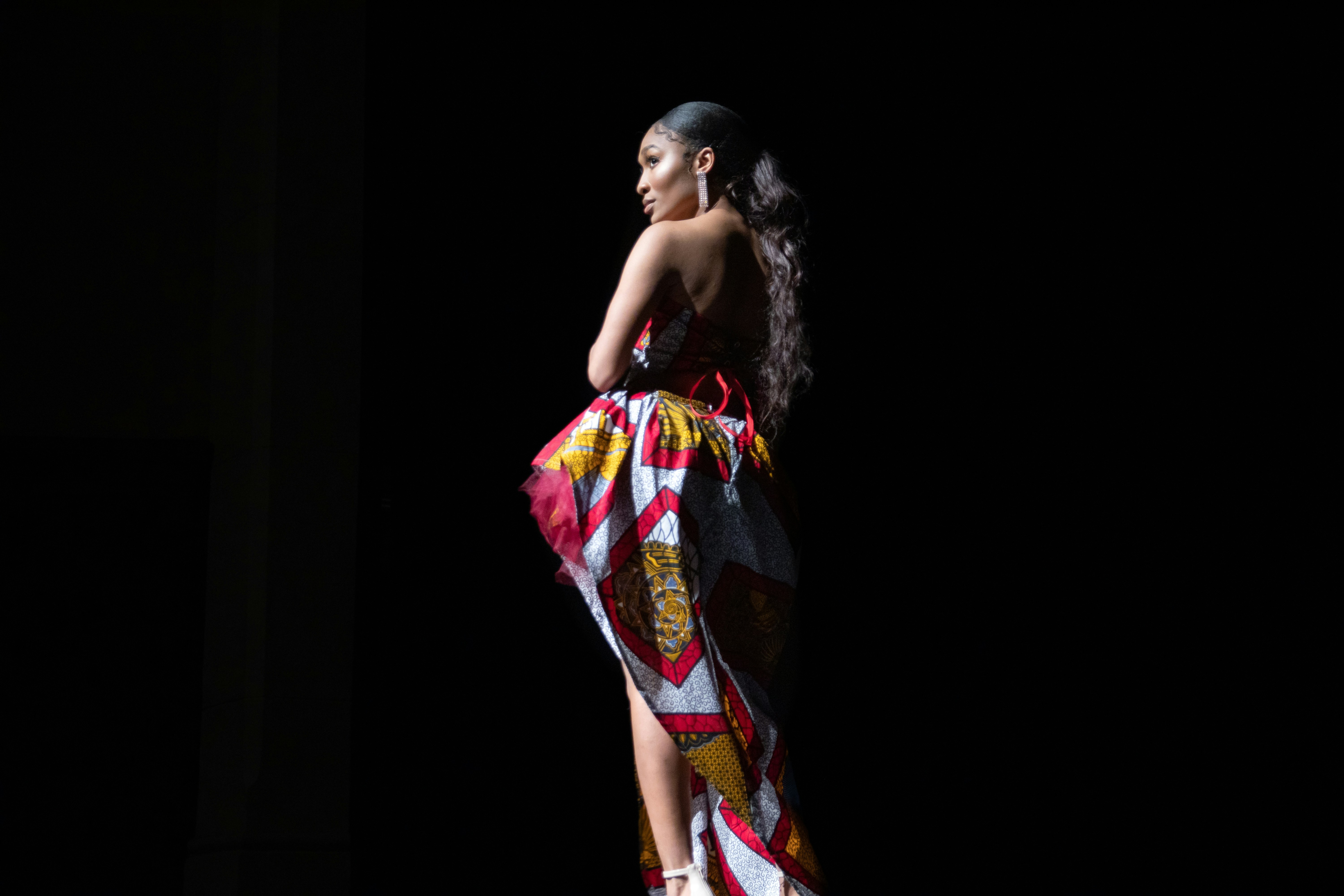 ドレスを着た女性が暗闇の中に立っている