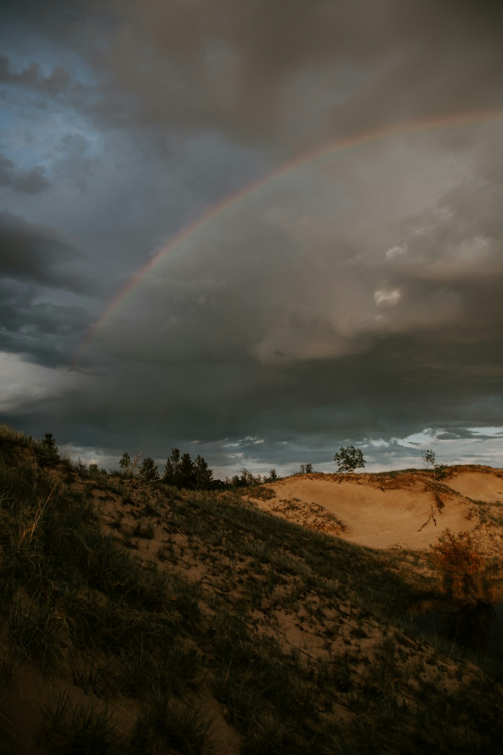 a rainbow in the sky over a sandy hill
