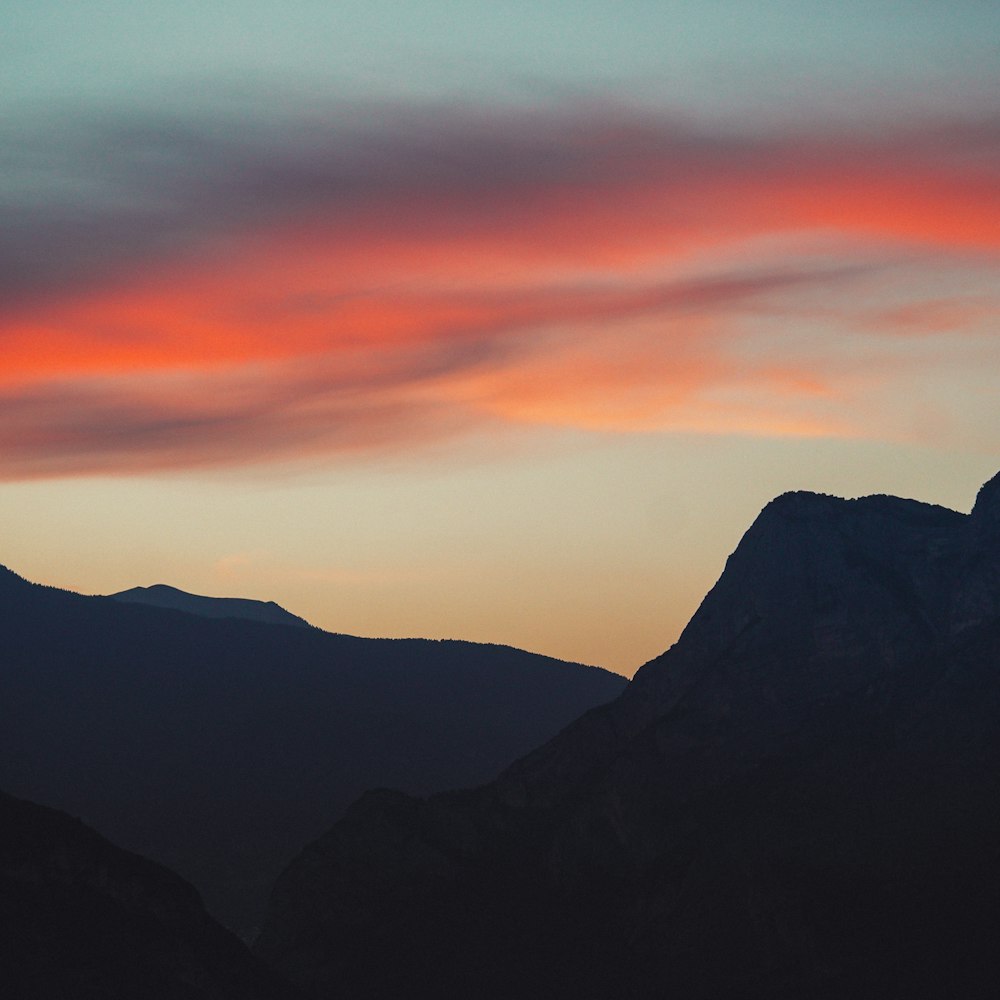Blick auf den Sonnenuntergang einer Bergkette mit einer roten Wolke am Himmel