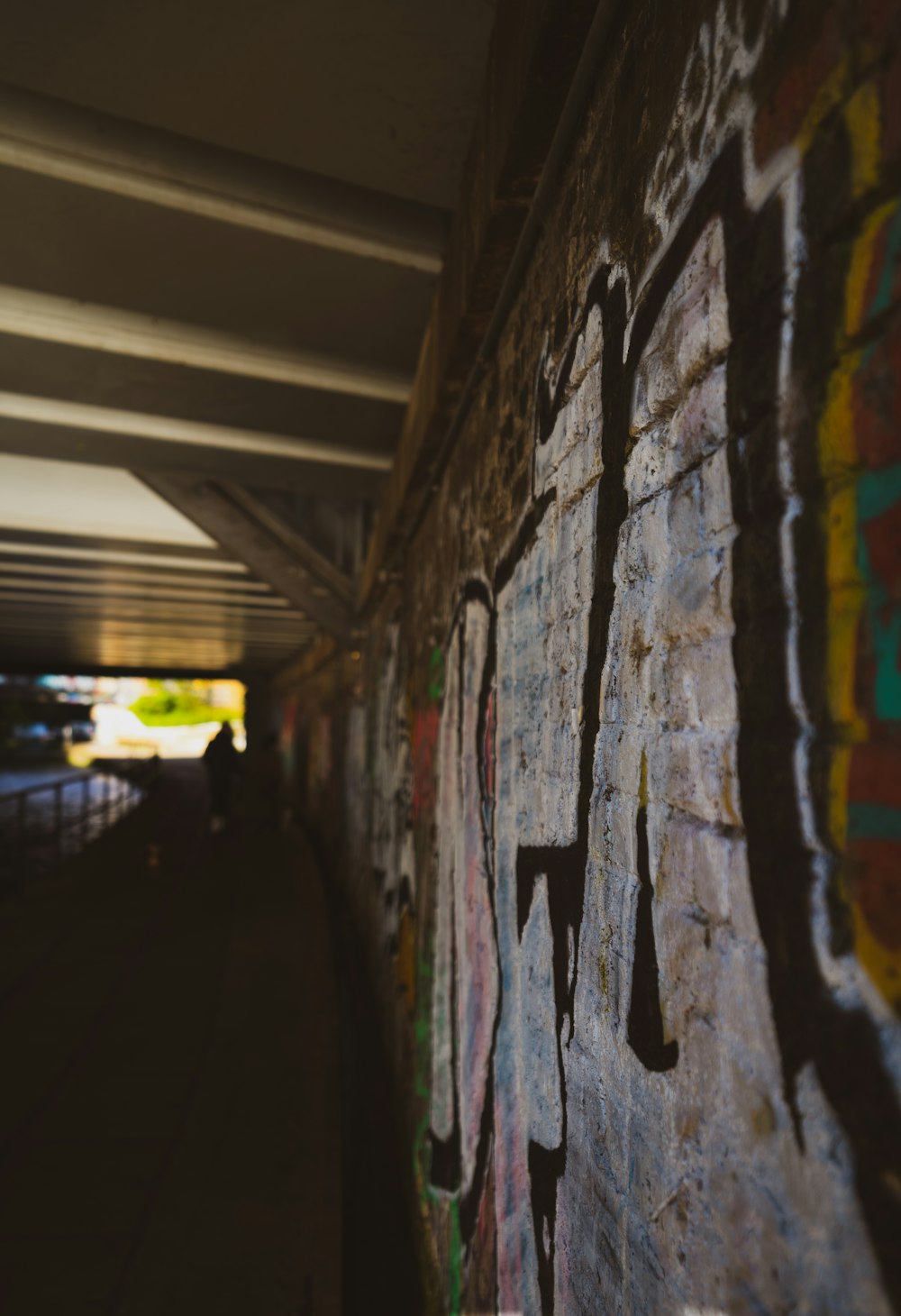 a wall covered in graffiti under a bridge