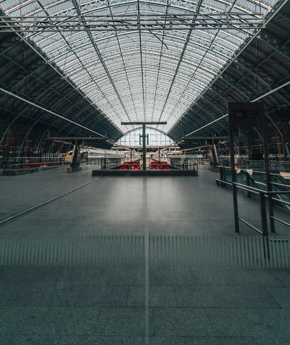 a train station with a glass ceiling and a train on the tracks