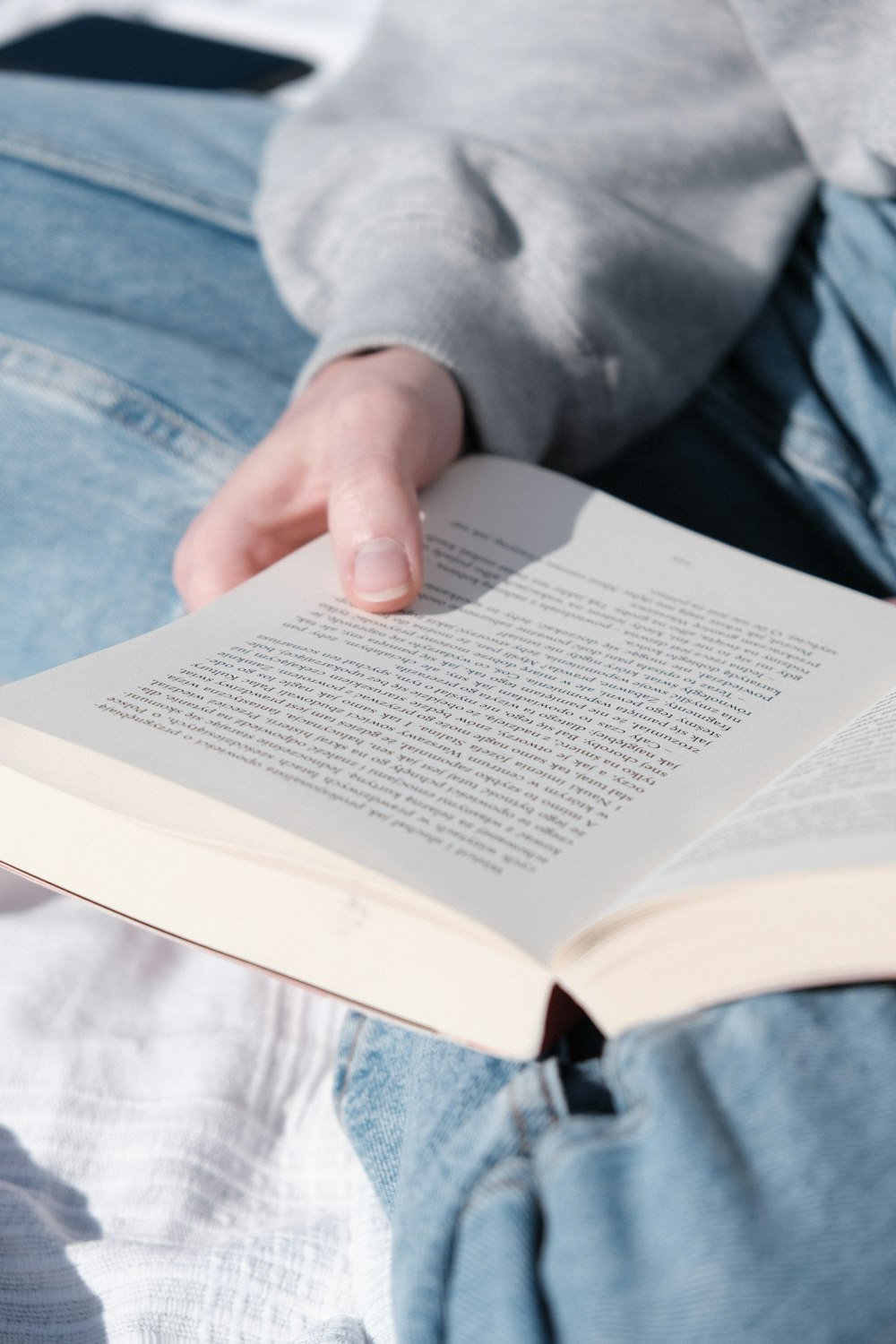 a person sitting on a bed reading a book