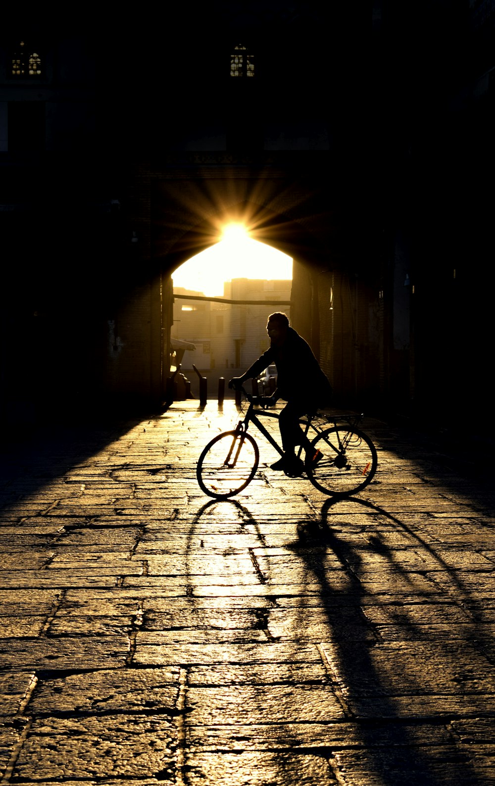 a man riding a bike down a street under a bridge