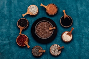 a variety of spices in wooden spoons on a blue surface