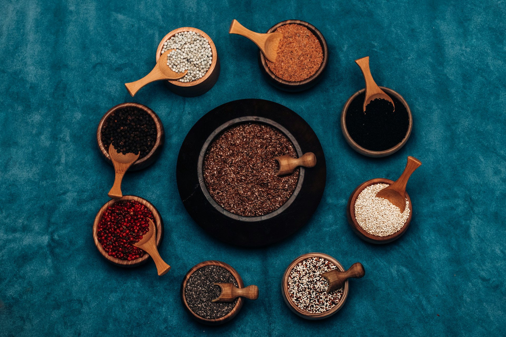 a variety of spices in wooden spoons on a blue surface