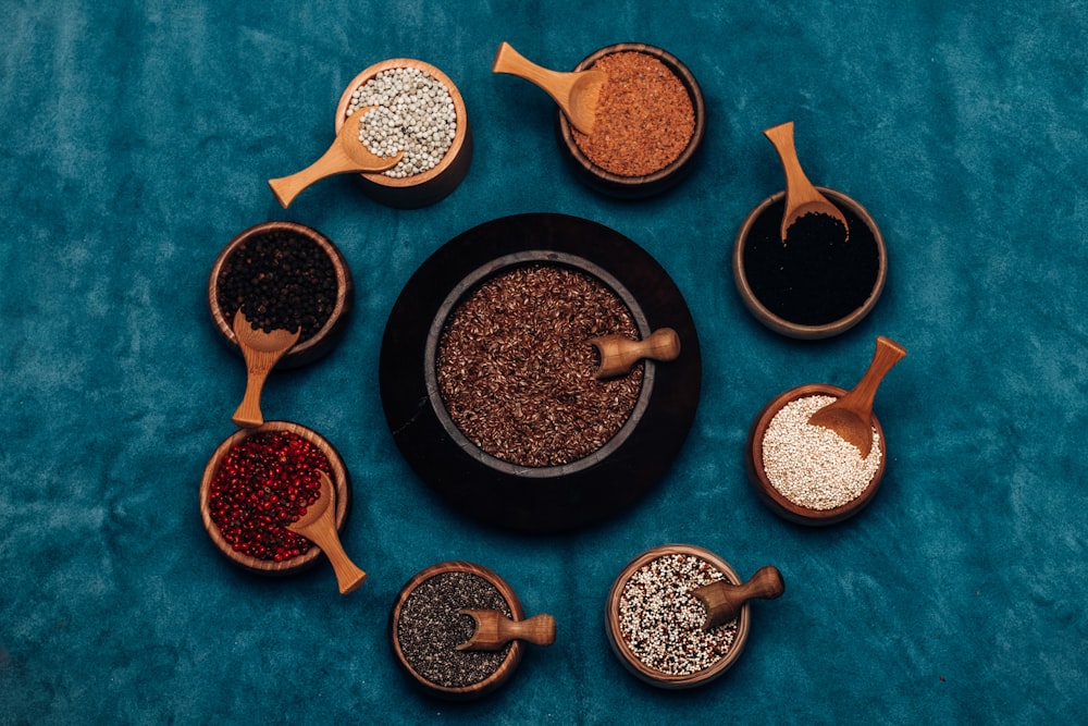 a variety of spices in wooden spoons on a blue surface