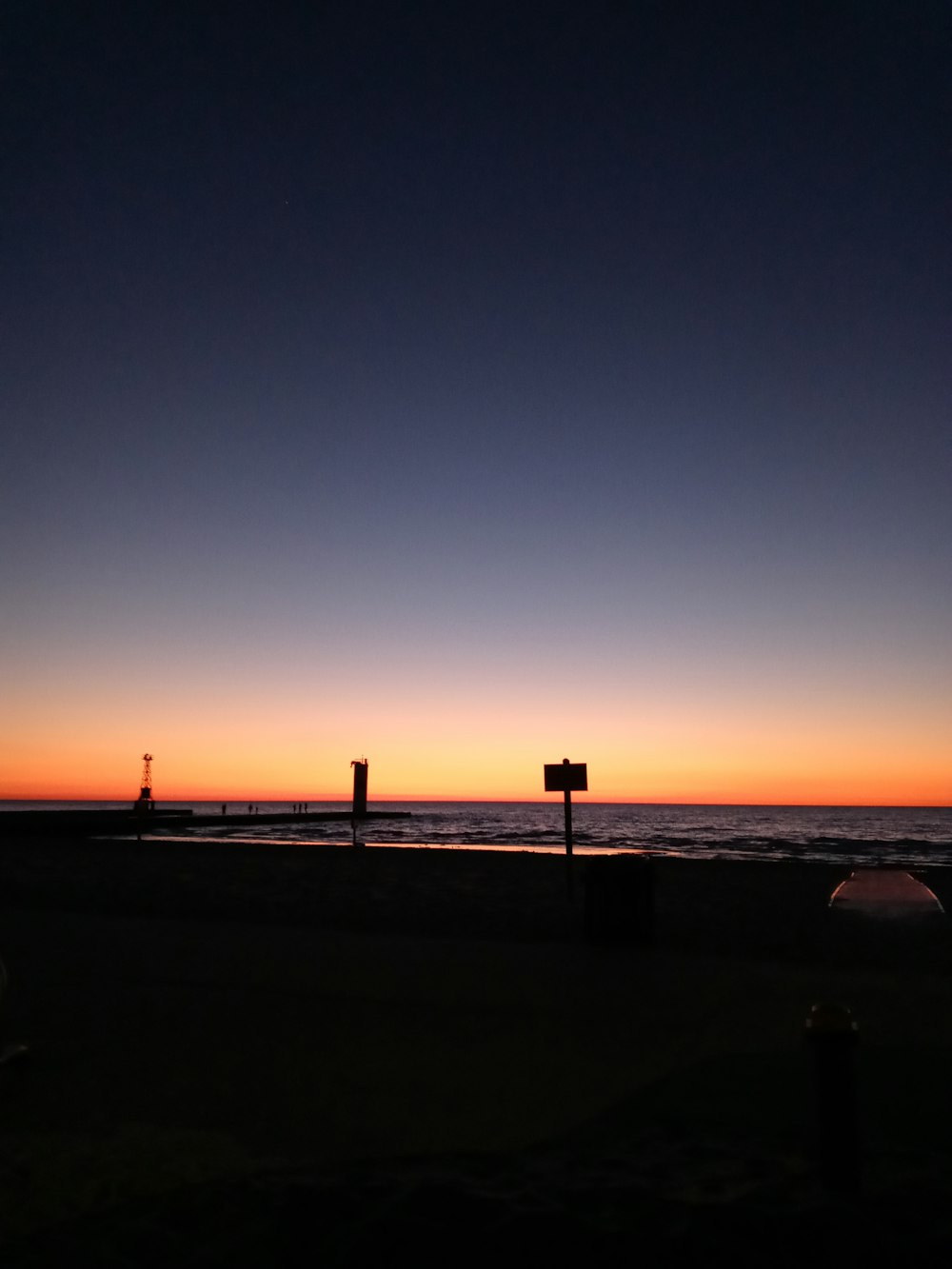 the sun is setting over the ocean and a street sign