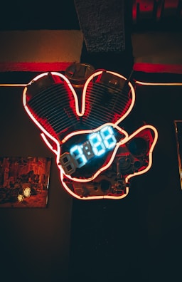 Vintage dragster with blown engine parked under neon lights.