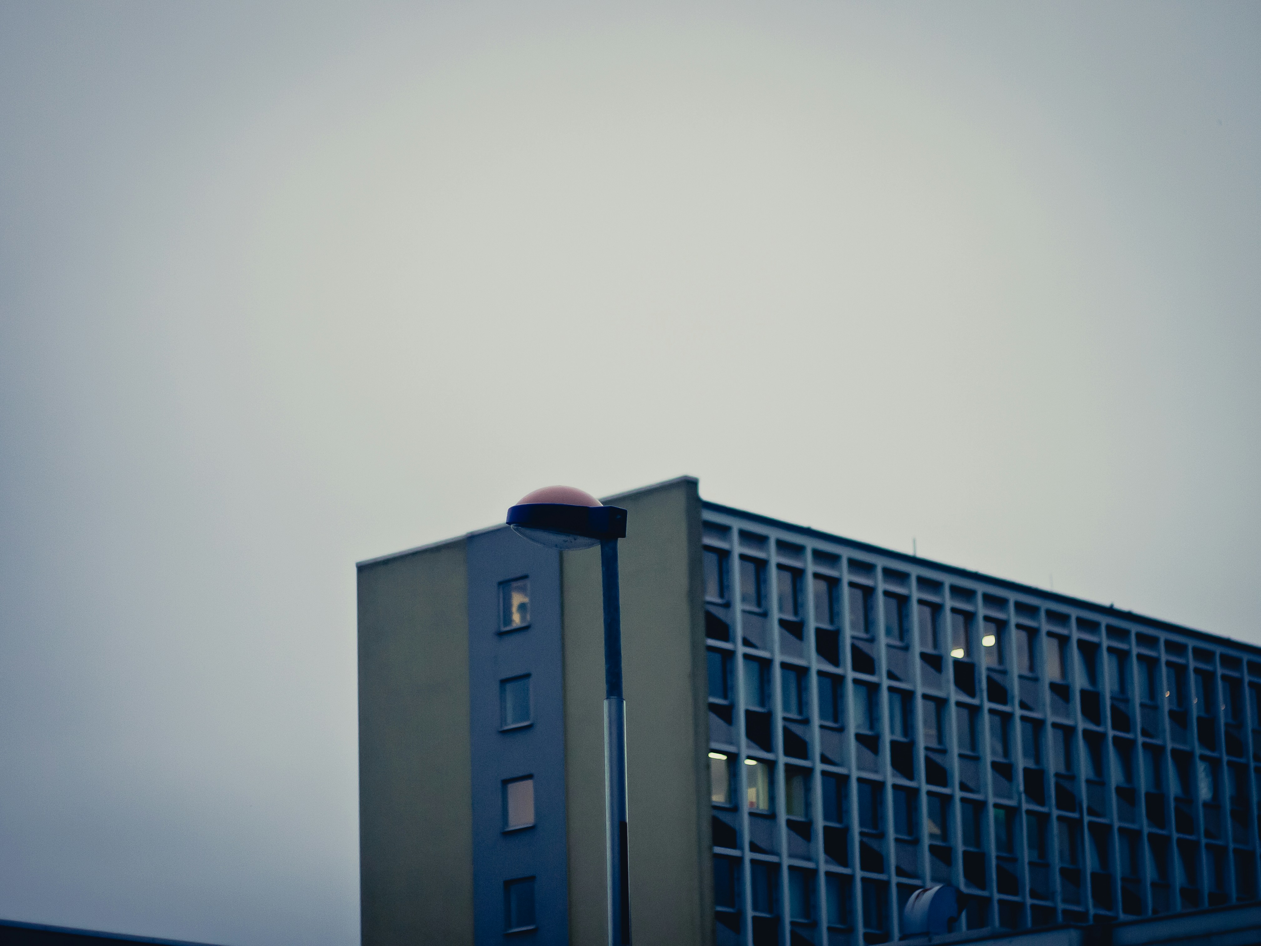 A somber, blurred photo of a modern high-rise building at dusk, with a sense of urban anonymity and quiet desperation