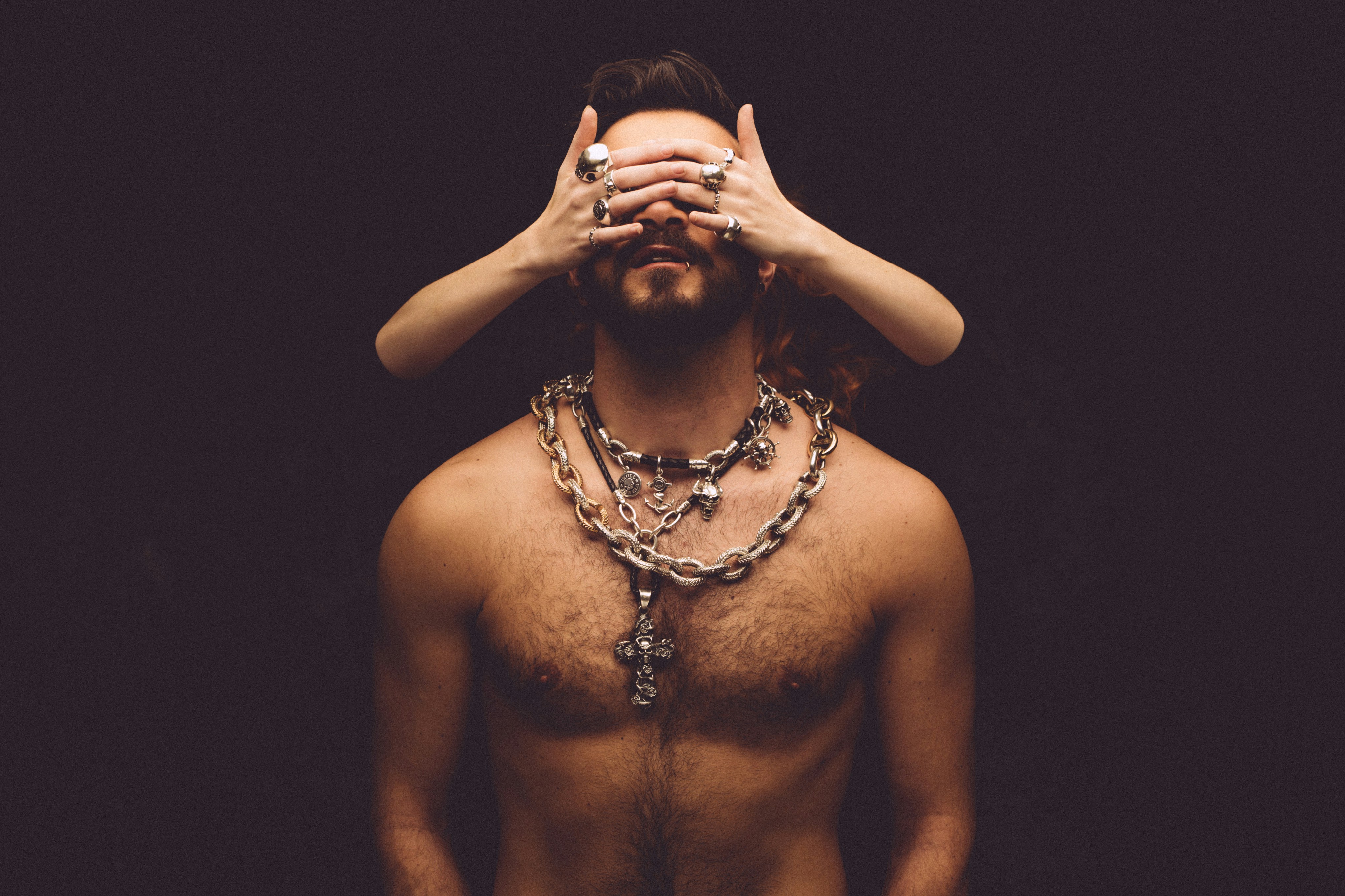 a shirtless man covering his eyes with his hands