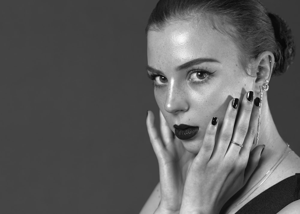 a black and white photo of a woman with her hands on her face