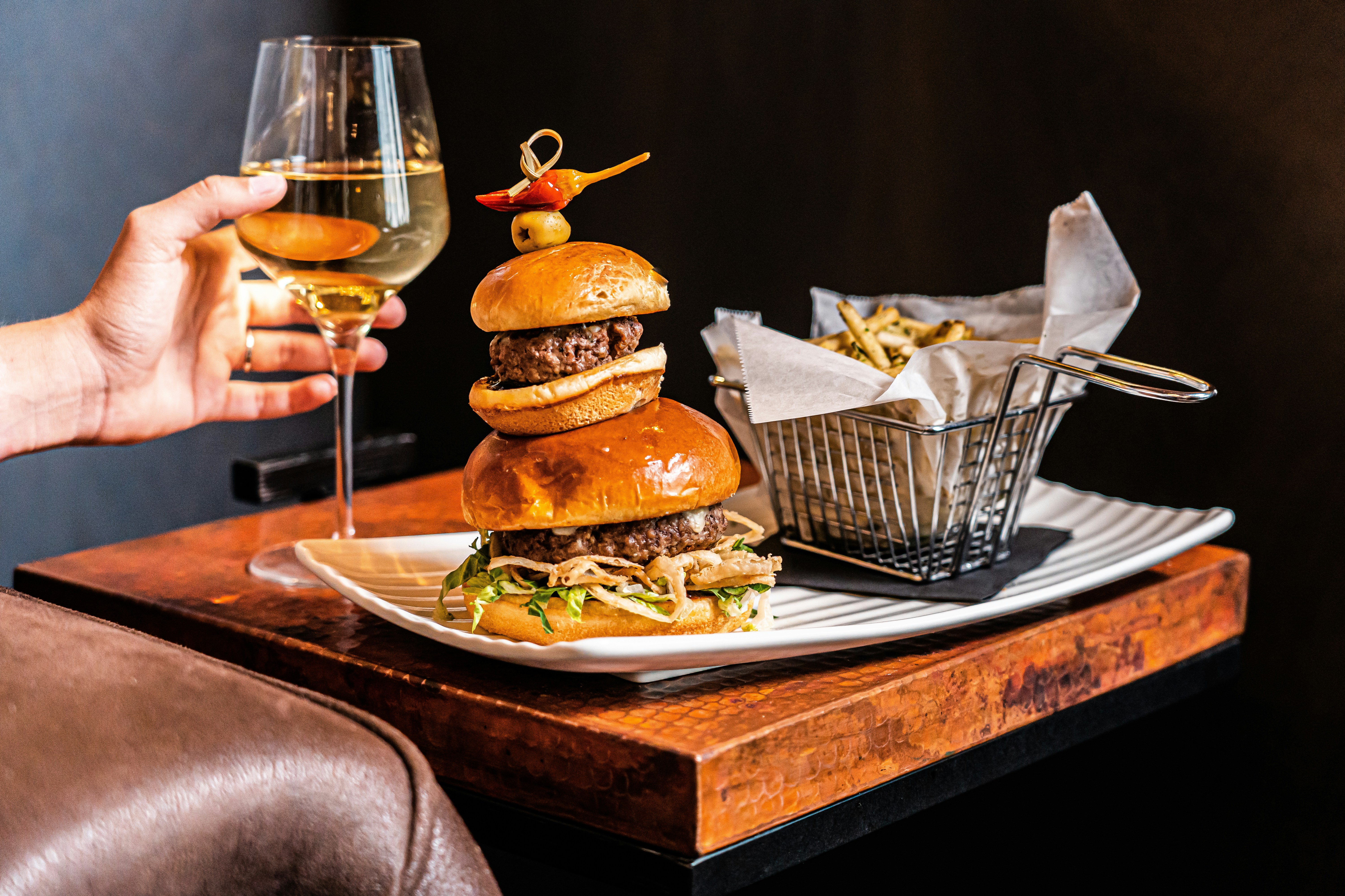 great photo recipe,how to photograph burger, wine and fries; a person holding a glass of wine over a plate of food