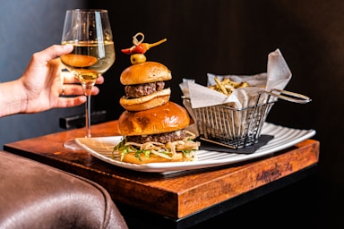 food photography,how to photograph burger, wine and fries; a person holding a glass of wine over a plate of food