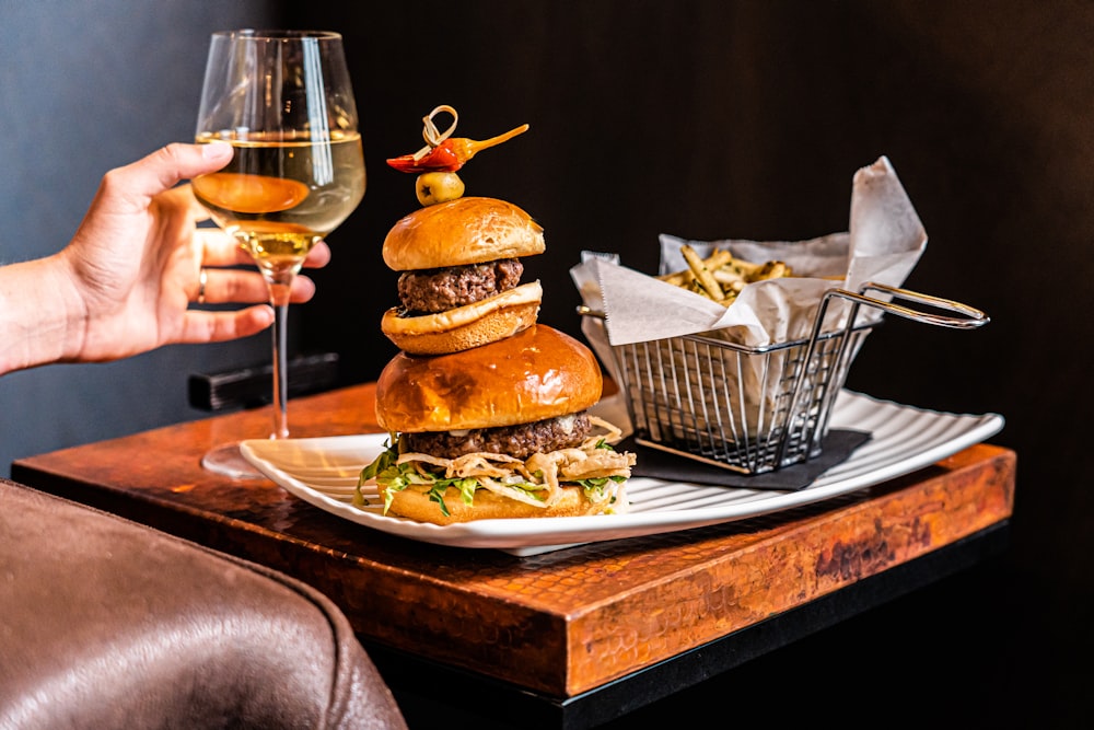 a person holding a glass of wine over a plate of food