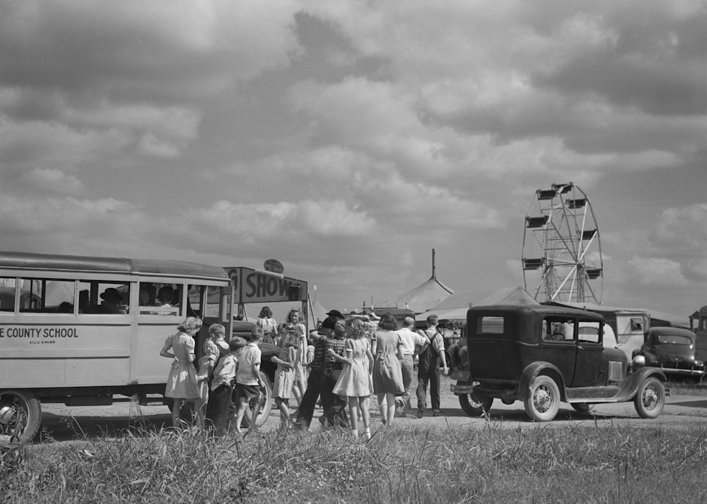 uma foto em preto e branco de um grupo de pessoas em pé na frente de um ônibus