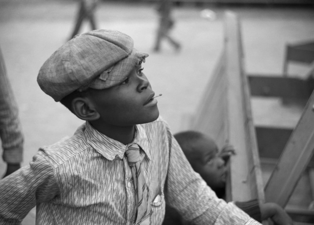 a young boy wearing a hat and tie