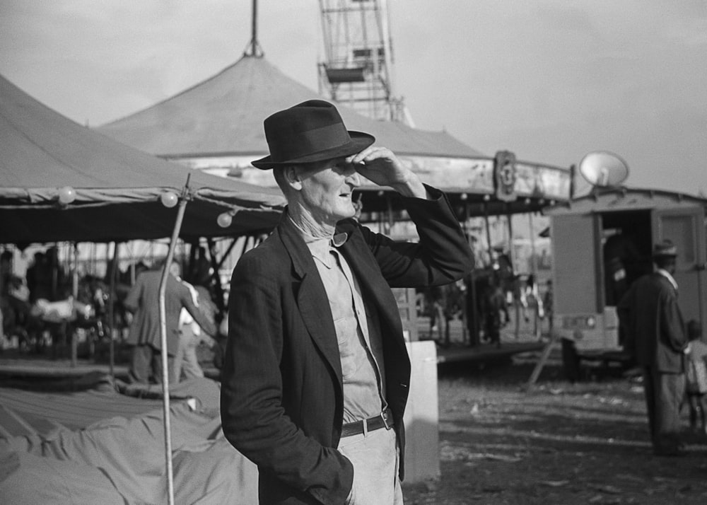 a man in a suit and hat standing in front of a tent