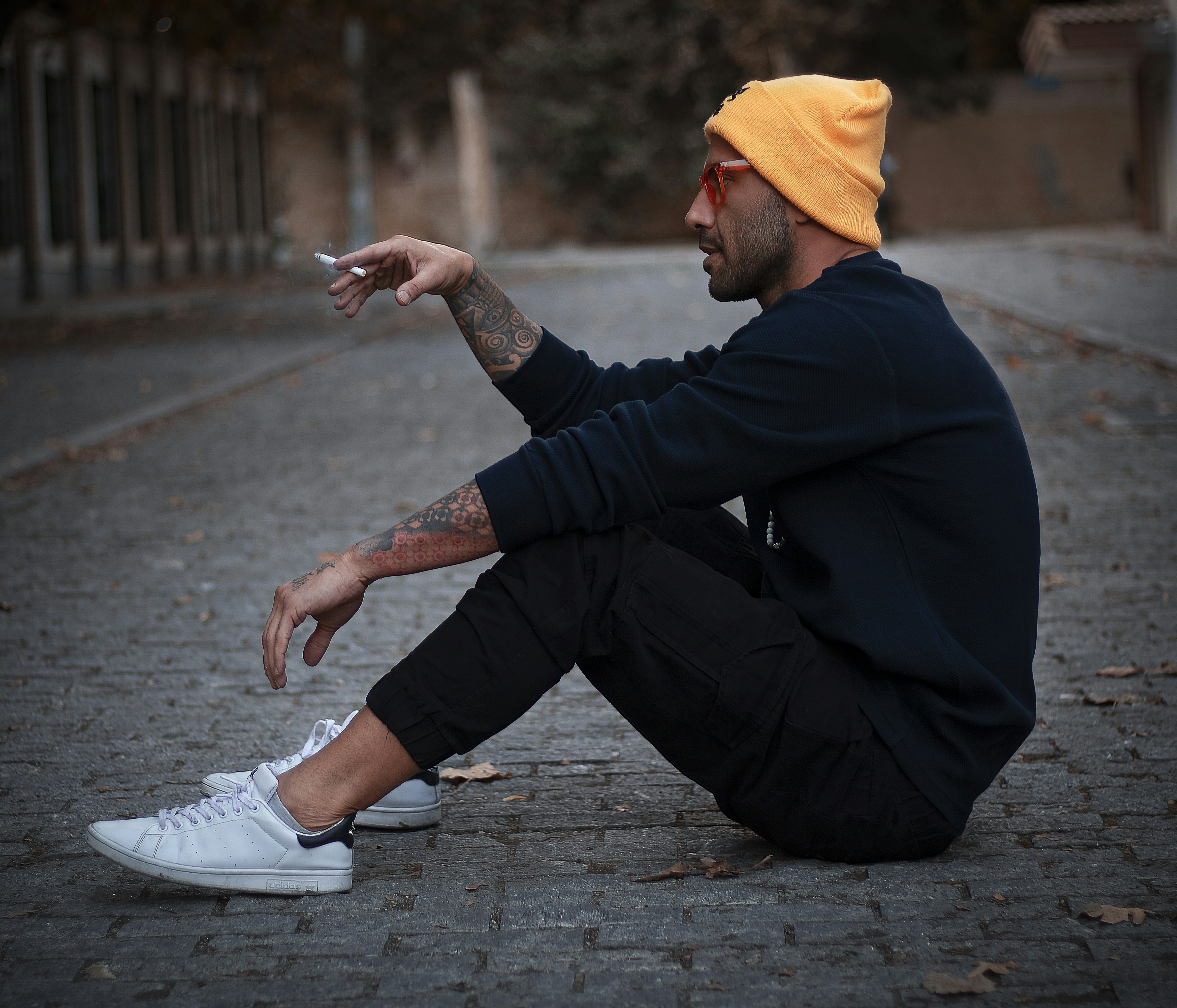 a man sitting on the ground smoking a cigarette