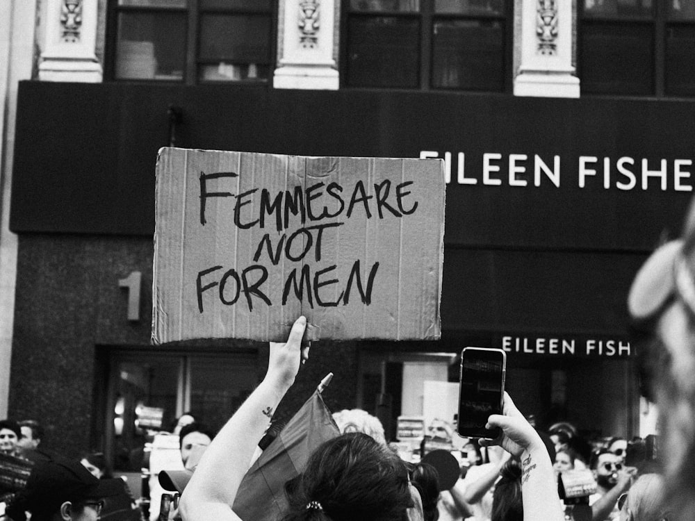 a man holding a sign that reads, feminists are not for men