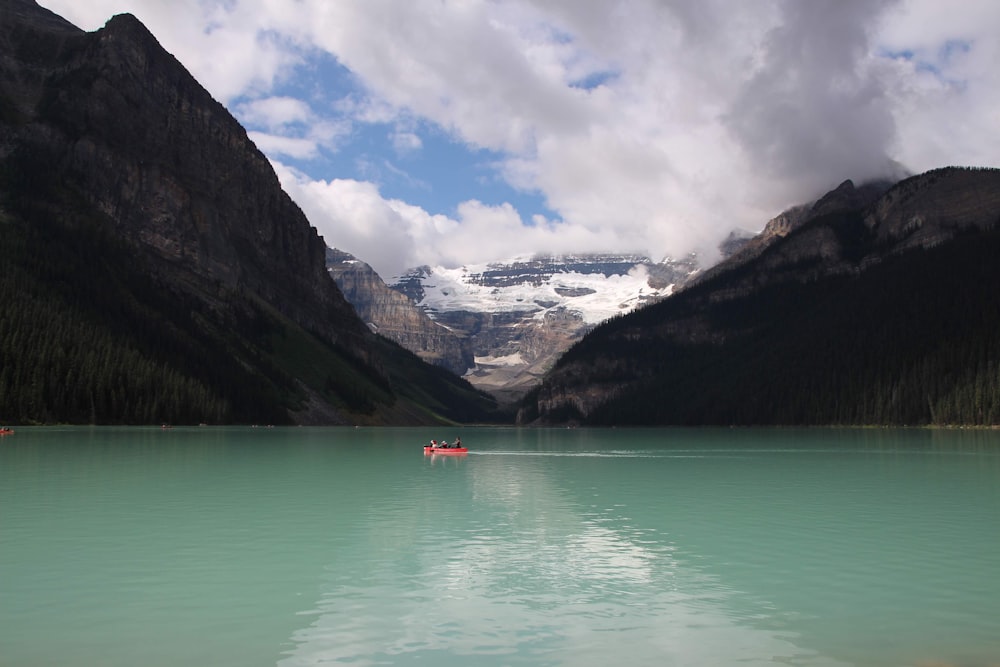 a boat floating on top of a lake surrounded by mountains