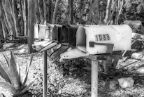 Stacked mailboxes with recently delivered letters and parcels on a sunny street.