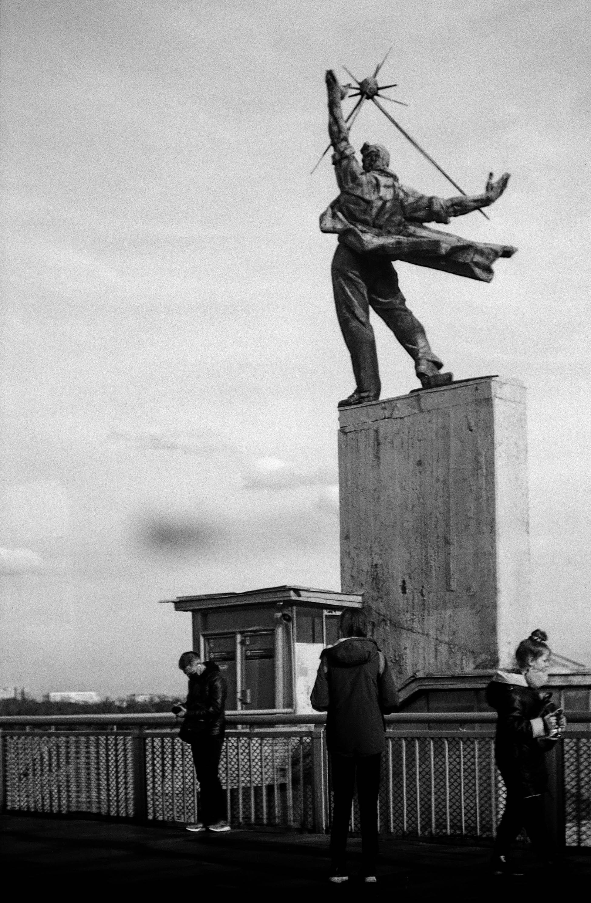 a black and white photo of a statue of a man holding a bow