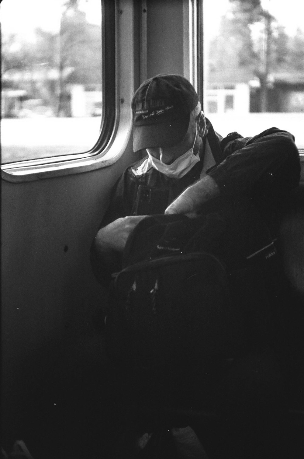 a black and white photo of a man sitting on a train