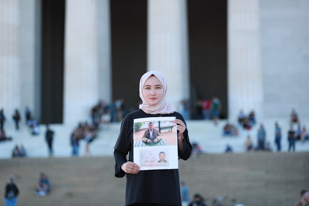 a woman in a hijab holding a picture of herself