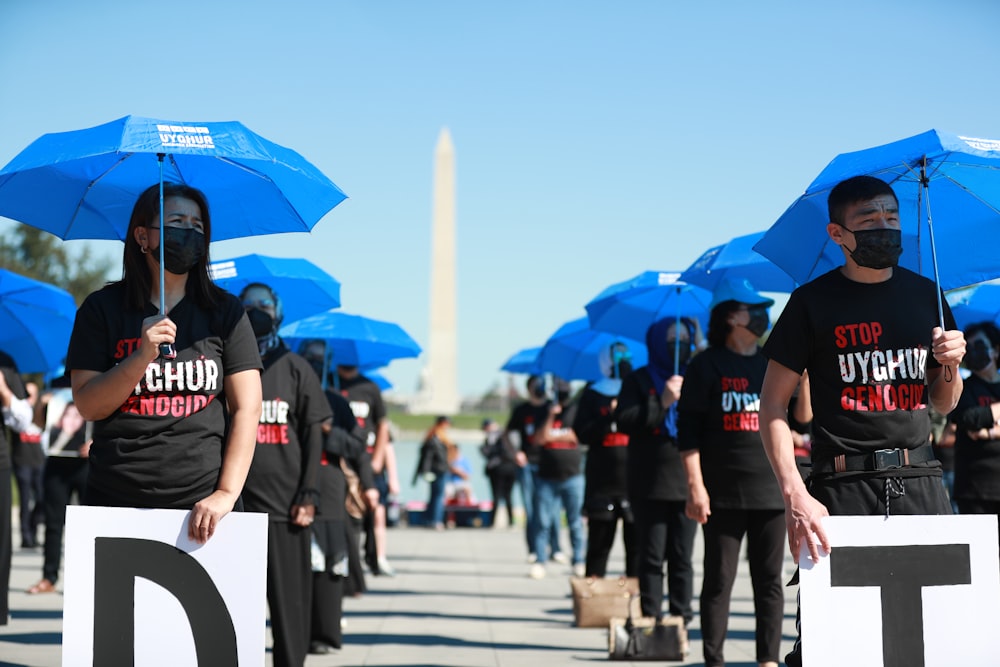 a group of people holding blue umbrellas in front of the washington monument