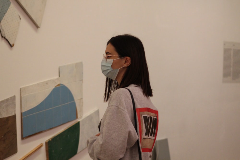 a woman wearing a face mask looking at art work